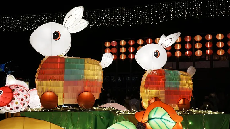 Two cartoon-like rabbit lanterns in bright colours lit up at a Mid-Autumn Festival lantern display at night