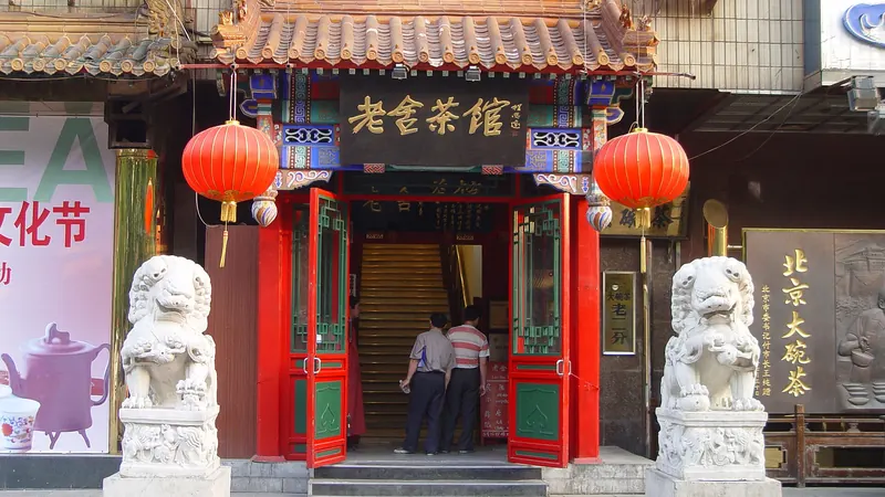 The entrance of Lao She Teahouse in Beijing, with red lanterns, painted eaves and two stone lions by the door
