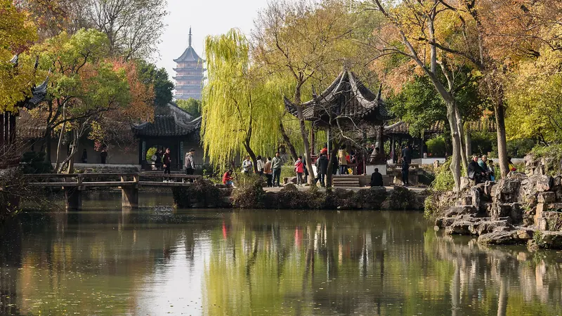 A still pond in the Humble Administrator's Garden in Suzhou, with willows, a pavilion and a distant pagoda in autumn