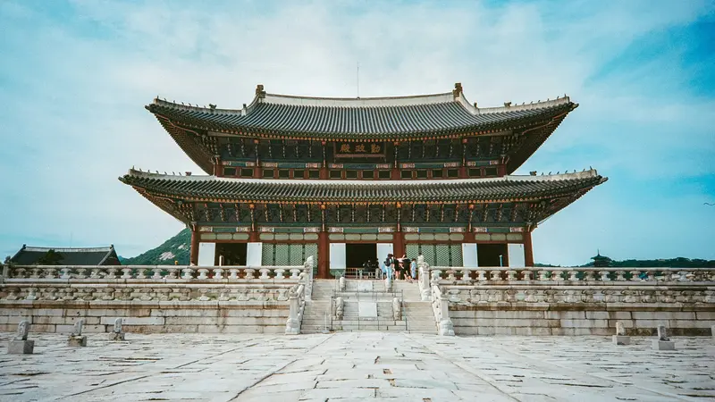 Geunjeongjeon, el salón del trono de dos pisos del palacio Gyeongbokgung en Seúl, tras un amplio patio de piedra bajo un cielo azul