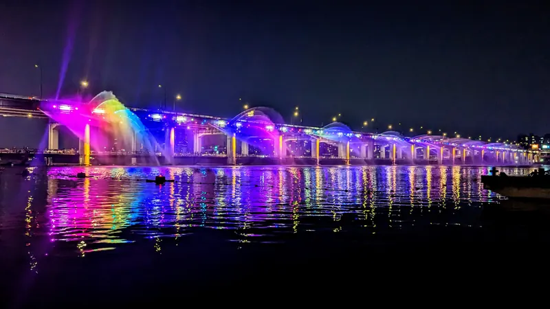 The Moonlight Rainbow Fountain on Banpo Bridge in Seoul at night, its colored water jets reflected in the Han River