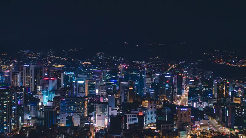 Downtown Seoul at night seen from above, with lit office towers and hills in the background