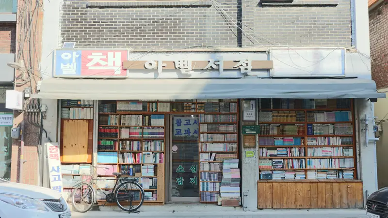 A used bookstore in Incheon with shelves of books behind its windows and a bicycle parked out front