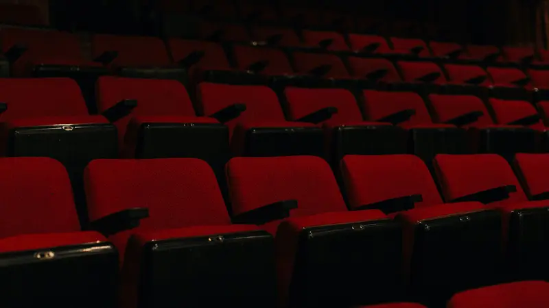Rows of empty red seats in a dark movie theater