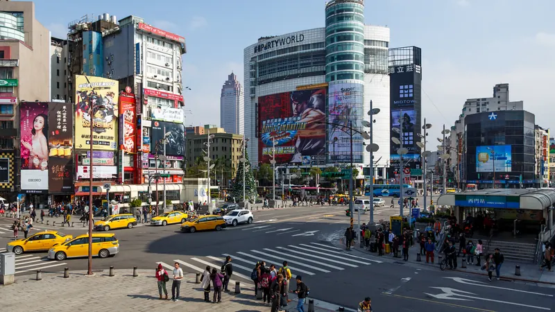 A busy intersection in Ximending, Taipei, with billboards, yellow taxis and crowds at a crosswalk