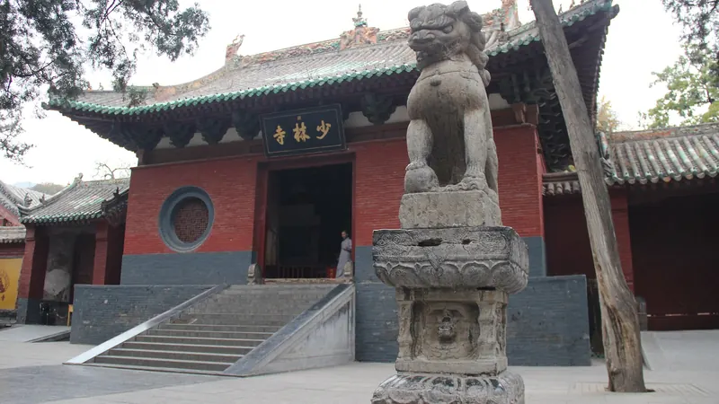 The red-walled main gate of Shaolin Temple in Henan, with stone steps and a carved stone lion in front