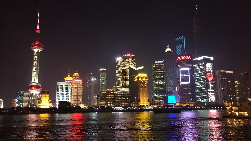 The lit Lujiazui skyline and Oriental Pearl Tower in Shanghai at night, reflected in the Huangpu River