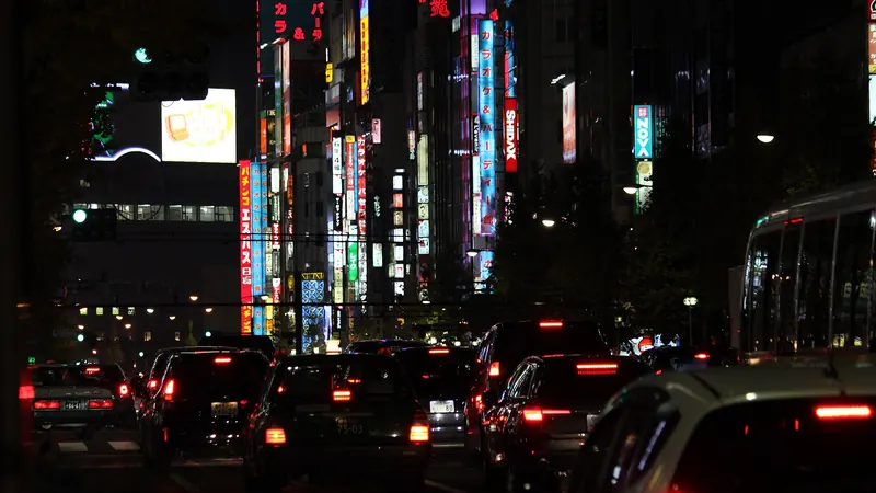 Neon signs glowing over traffic on a street in Kabukicho, Shinjuku, Tokyo, at night