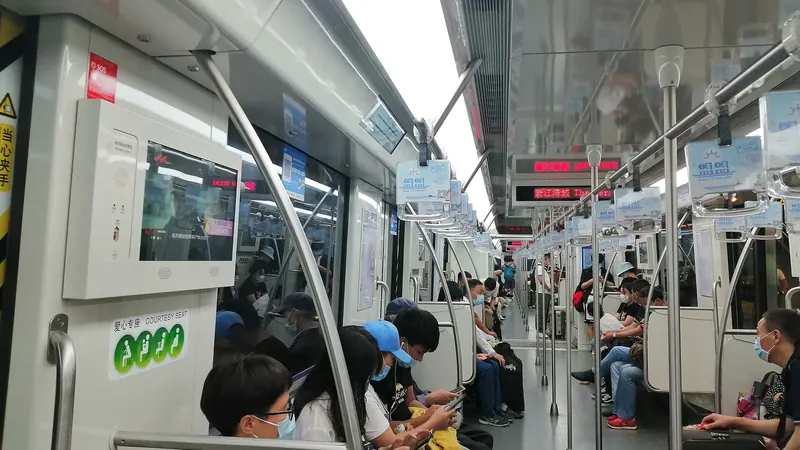 Passengers seated in a Shanghai Metro Line 10 carriage, several of them looking down at their phones