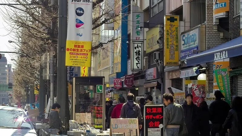 A crowded sidewalk on Akihabara's main street in Tokyo, crammed with vertical shop signs in Japanese