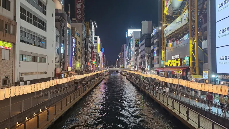 The Dotonbori canal in Osaka at night, lined with paper lanterns and bright shop signs on both banks