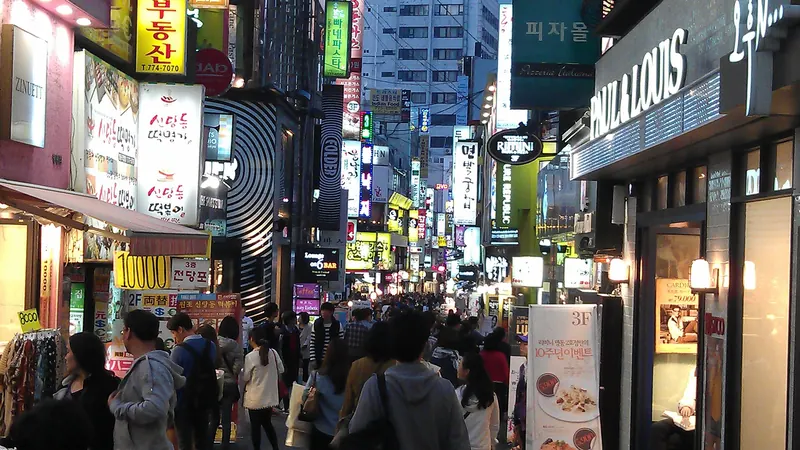Evening crowds on a Myeongdong shopping street in Seoul, lined with bright shop signs in Hangul