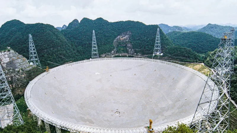 The giant FAST radio telescope dish set in a karst valley among green hills in Guizhou, China