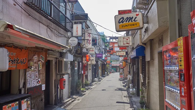 A narrow lane of tiny bars in Golden Gai, Shinjuku, lined with hanging signs, lanterns and a vending machine