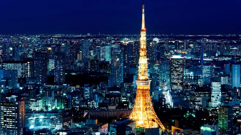 Tokyo Tower lit orange at night among the glittering office towers of central Tokyo, seen from above