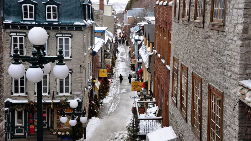 A snowy pedestrian lane of old stone houses and globe street lamps in the lower town of Quebec City in winter