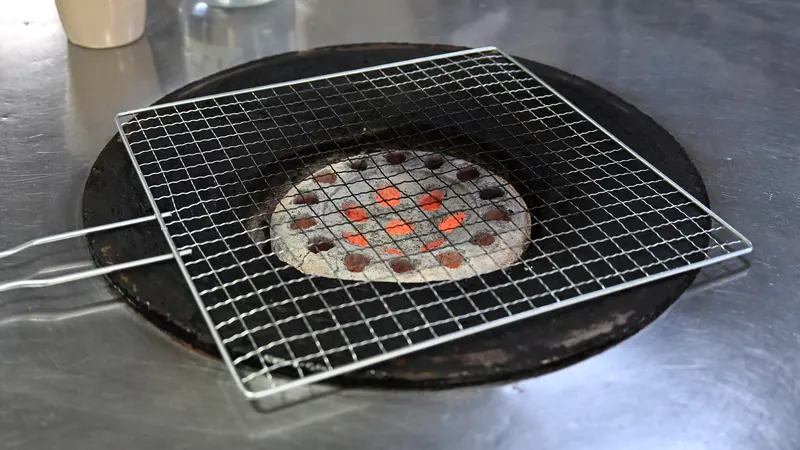 A glowing yeontan coal briquette under a wire grill set into a metal table at a Korean barbecue restaurant