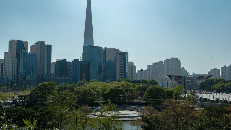 Lotte World Tower rising over the trees and ponds of Seoul Olympic Park on a clear day