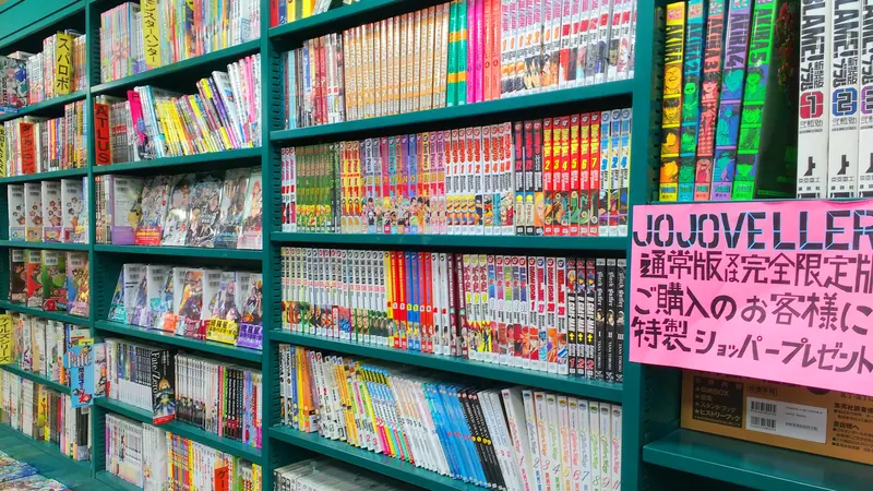 Tall green shelves packed with manga volumes, spines out, in a comics bookshop in Kyoto, Japan